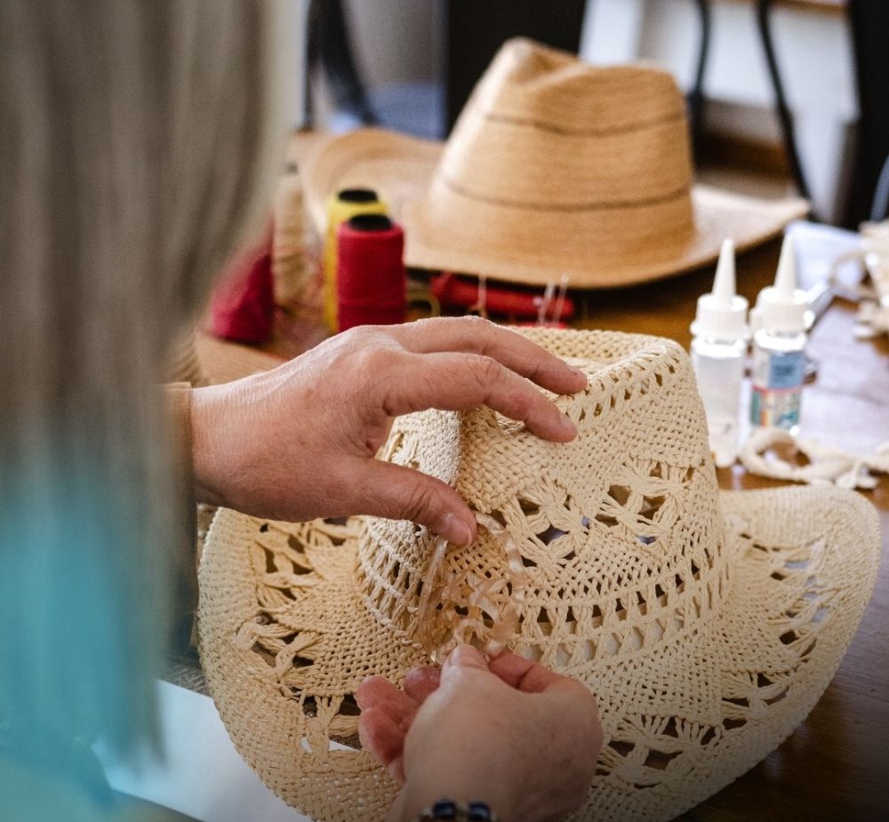 Manos decorando un sombrero de paja artesanal